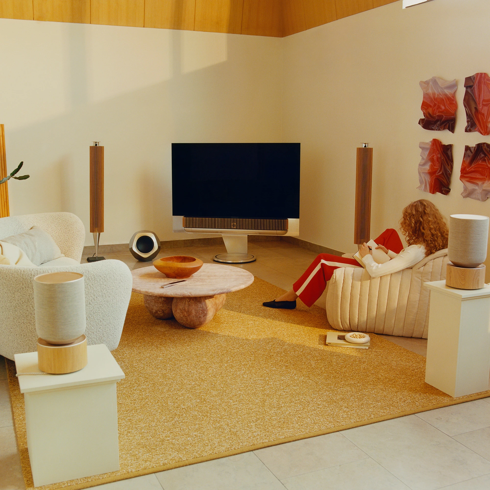 Woman sitting in living room with a range of Bang & Olufsen speakers
