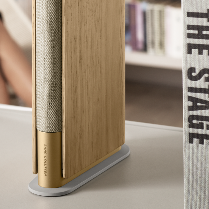 Close view of the compact speaker Beosound Emerge Gold Tone - Light Oak placed on a bookshelf at home