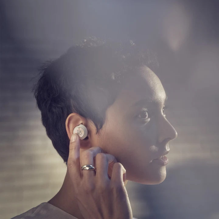 A woman using the touch controls on her Beoplay EQ earbud