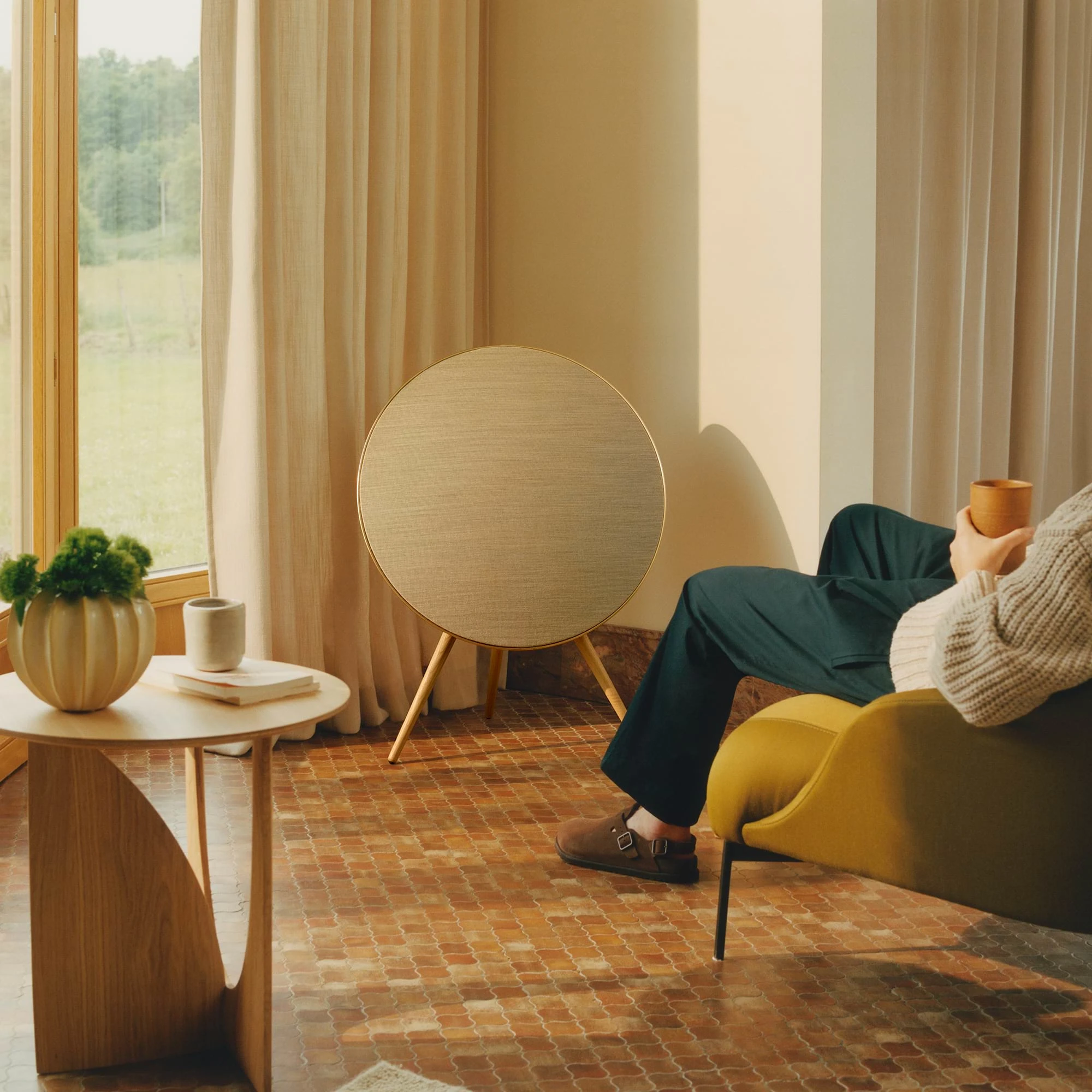 Beosound A9 placed in a living room while a person sits on a chair next to it