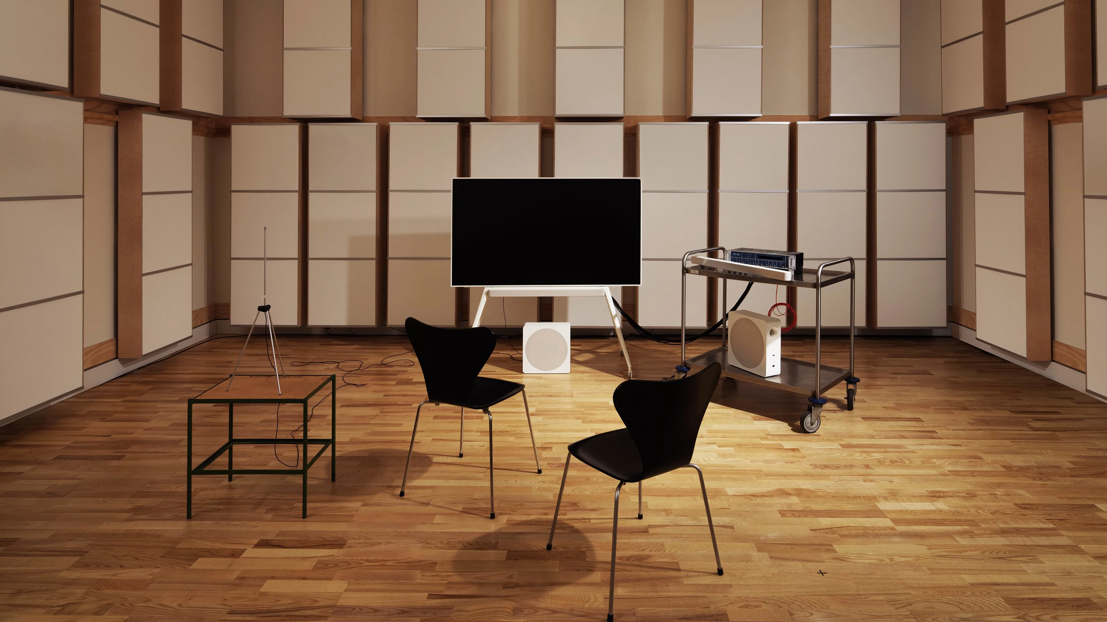 A tv placed centered in a room with two chairs and electronic devices
