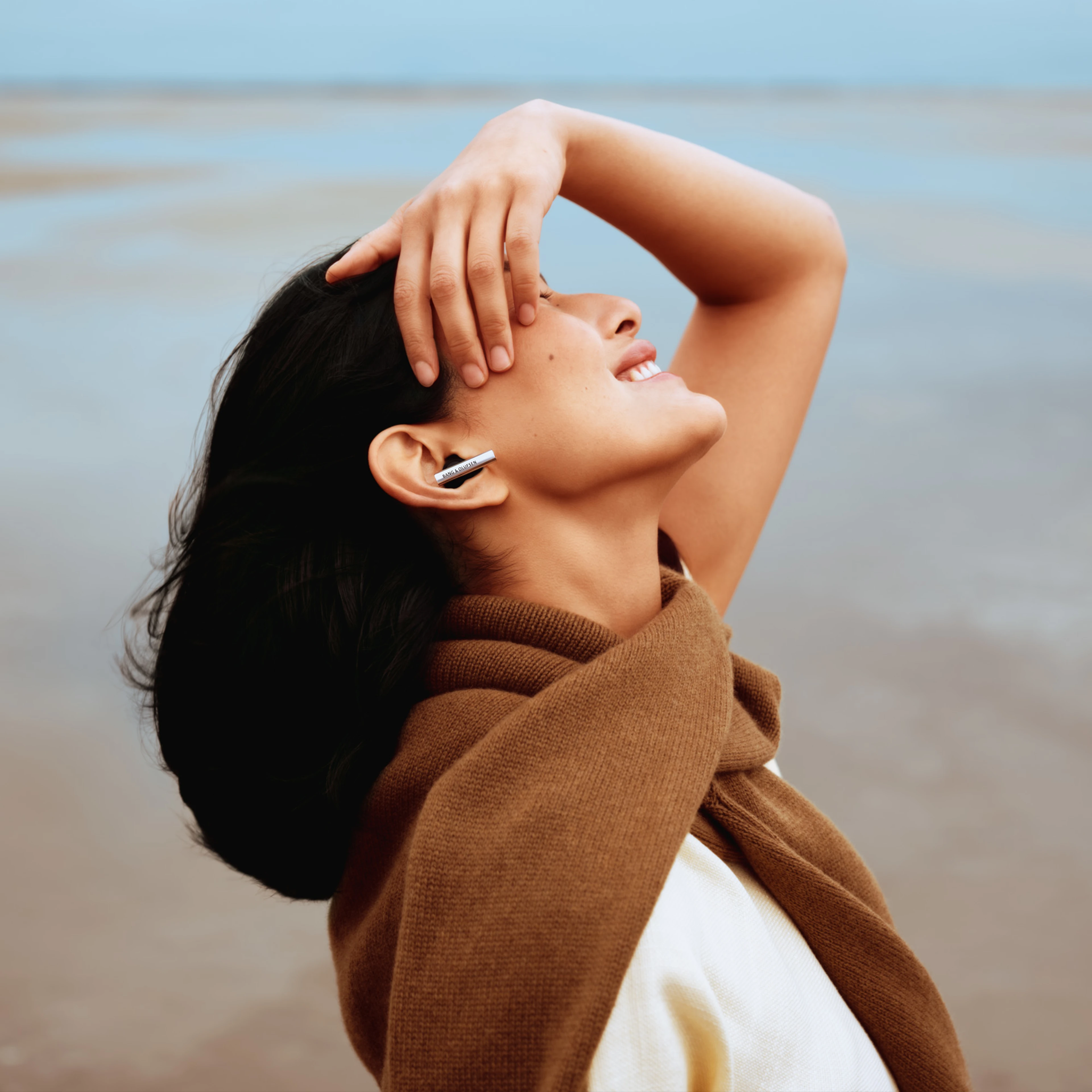 Smilende kvinde set i profil med Beo Grace i ørerne og nyder musikken