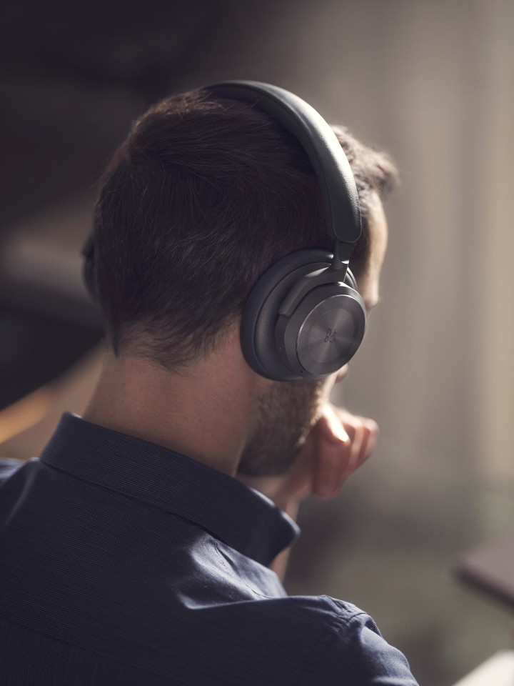 A man wearing Beoplay HX Black while working