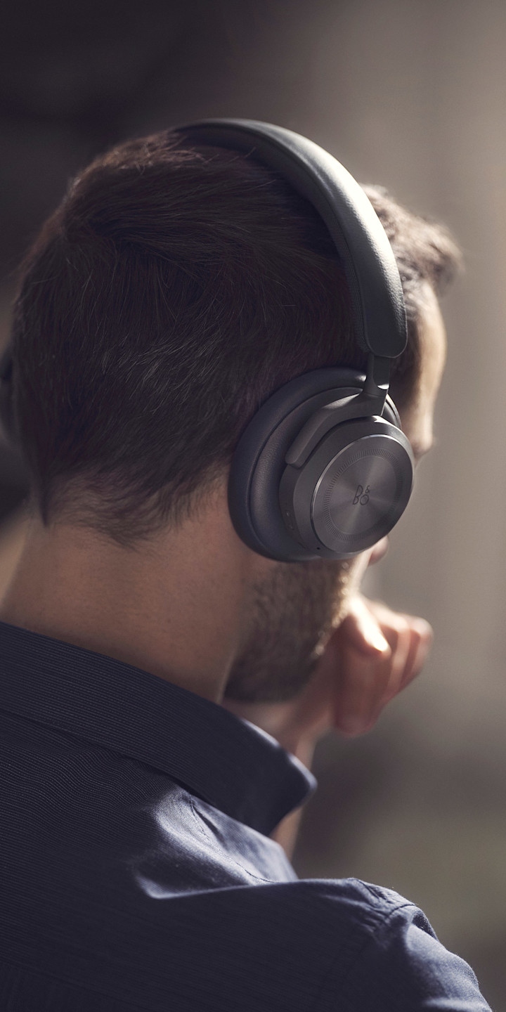 A man wearing Beoplay HX Black while working