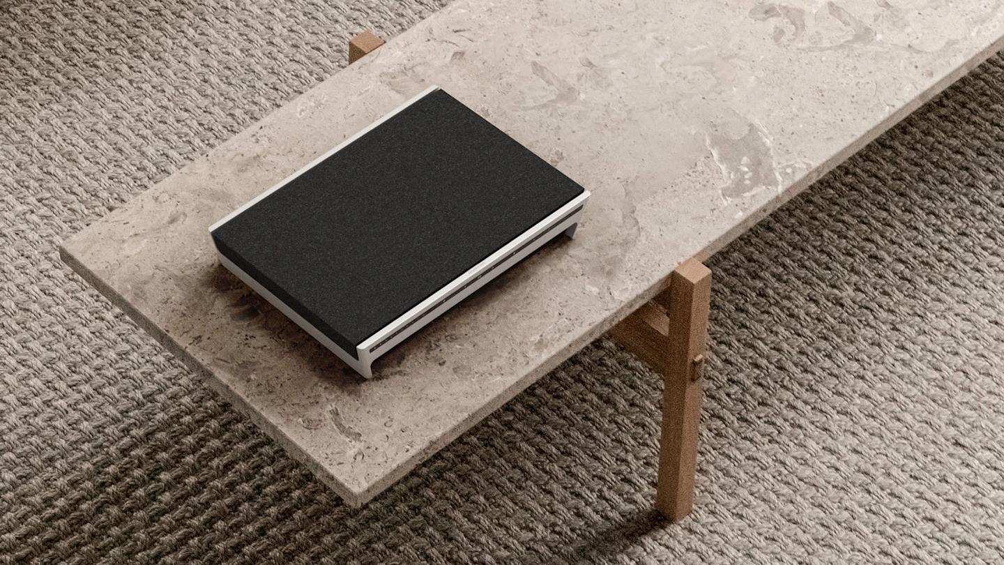 Beosound Level Natural - Dark Grey laid down on a marble table