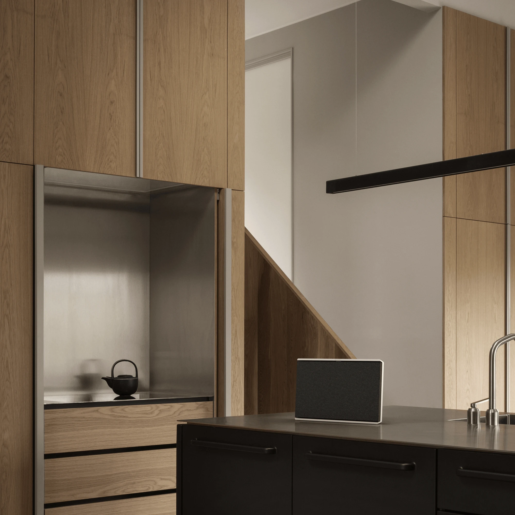 Une enceinte Beosound Level Gold Tone/Light Oak disposée verticalement sur une table pendant le petit-déjeuner