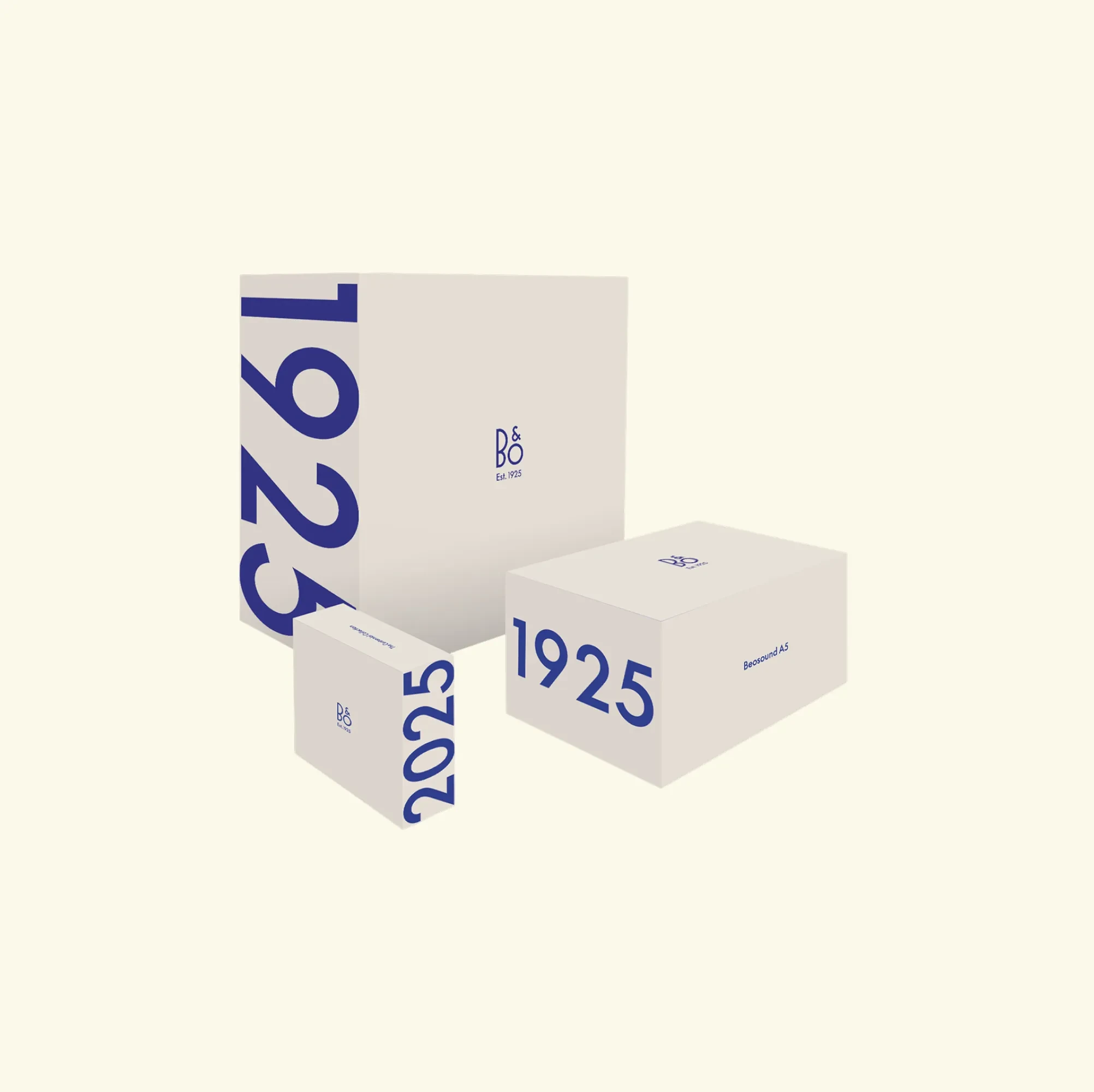 Three white B&O packaging boxes with blue "1925" text and logo, arranged on cream background.