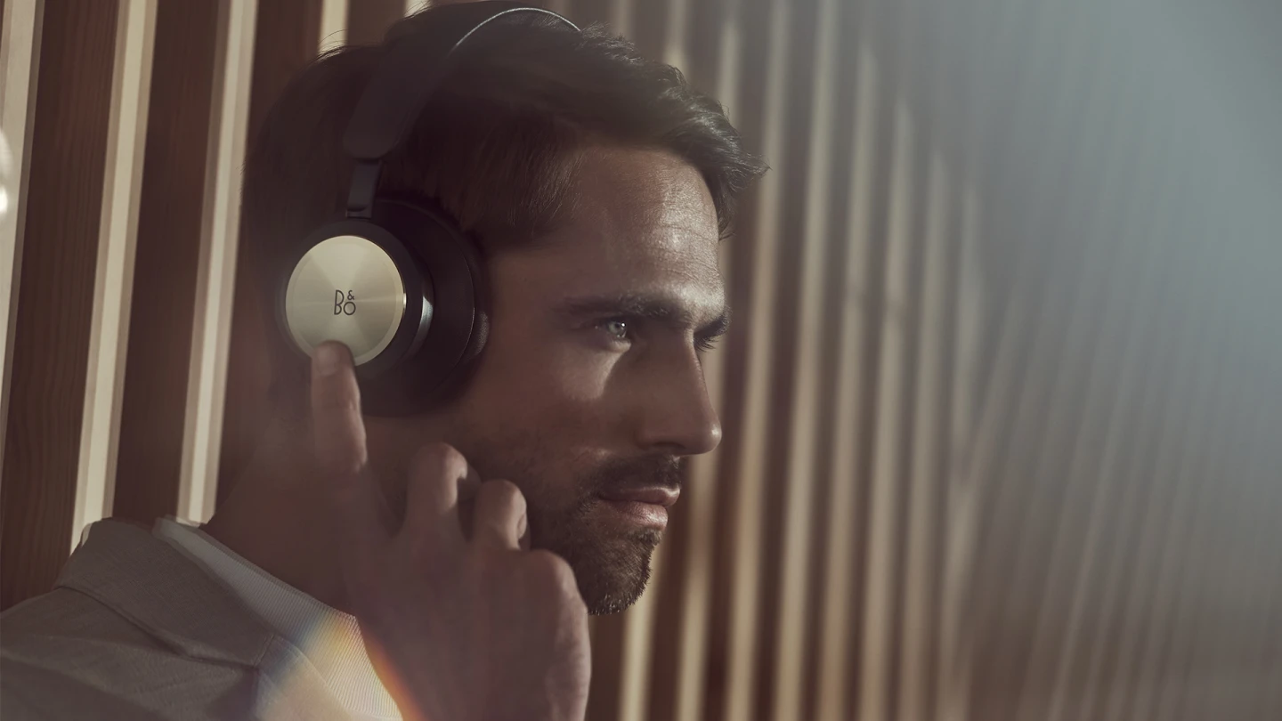 A man using the touch interface on Beoplay Portal earcup