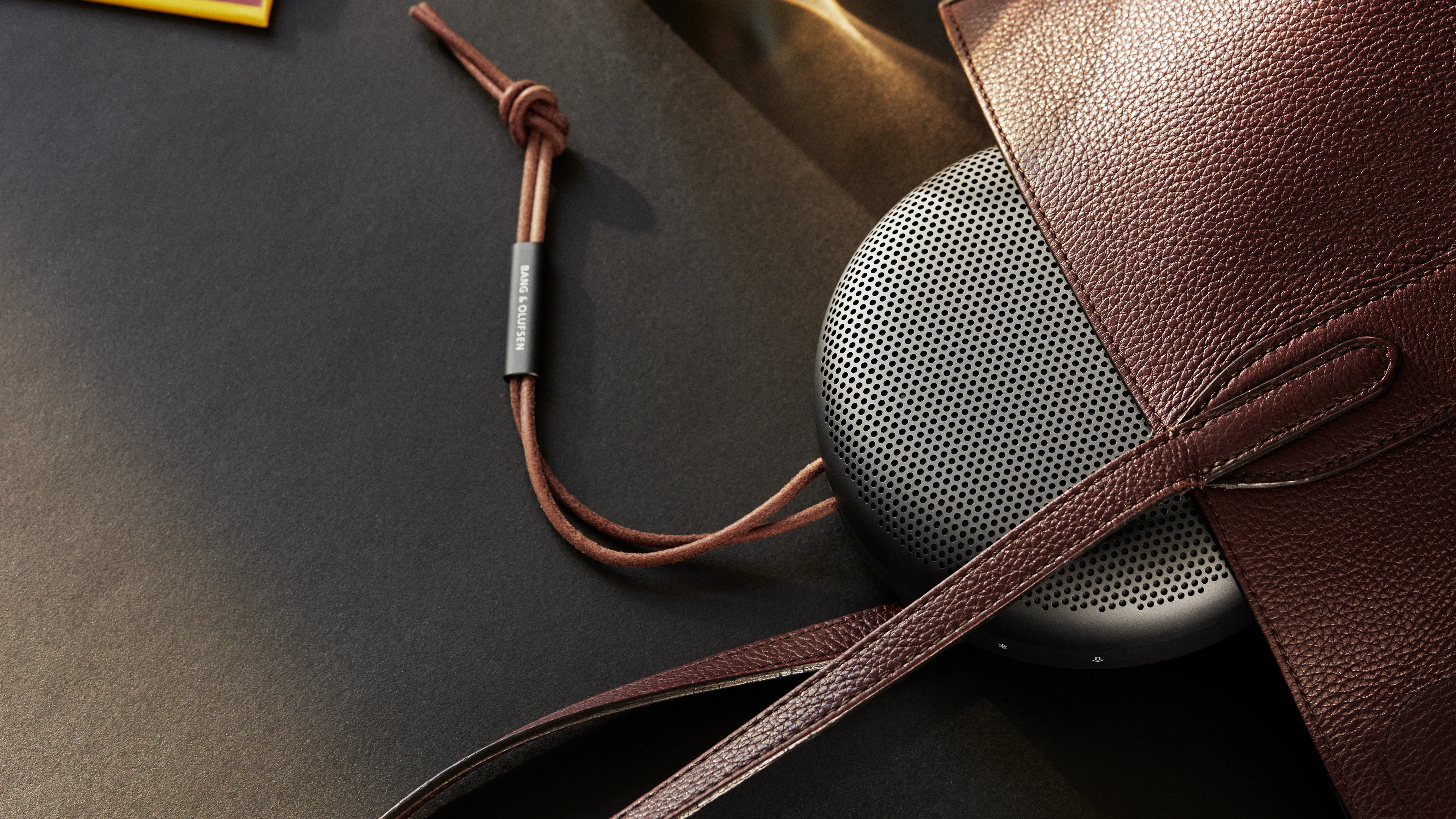 Beosound A1 sobre una mesa negra con una bolsa marrón