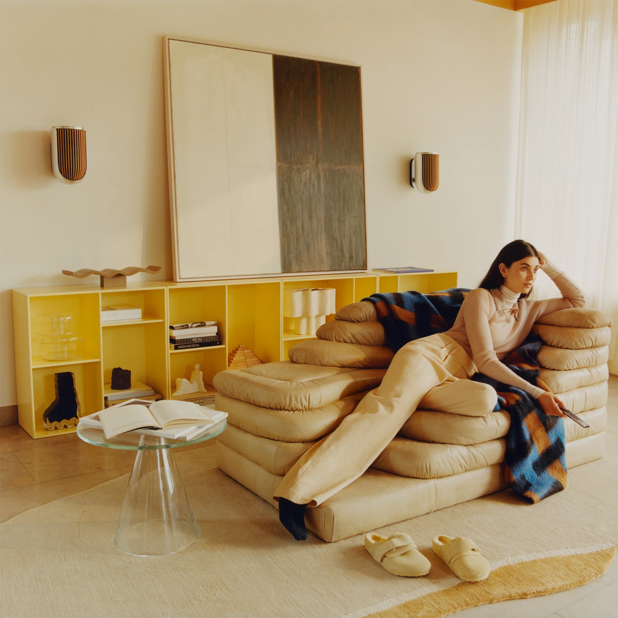 A woman sitting holding a remote, in a room with Beolab 8 speaker set 