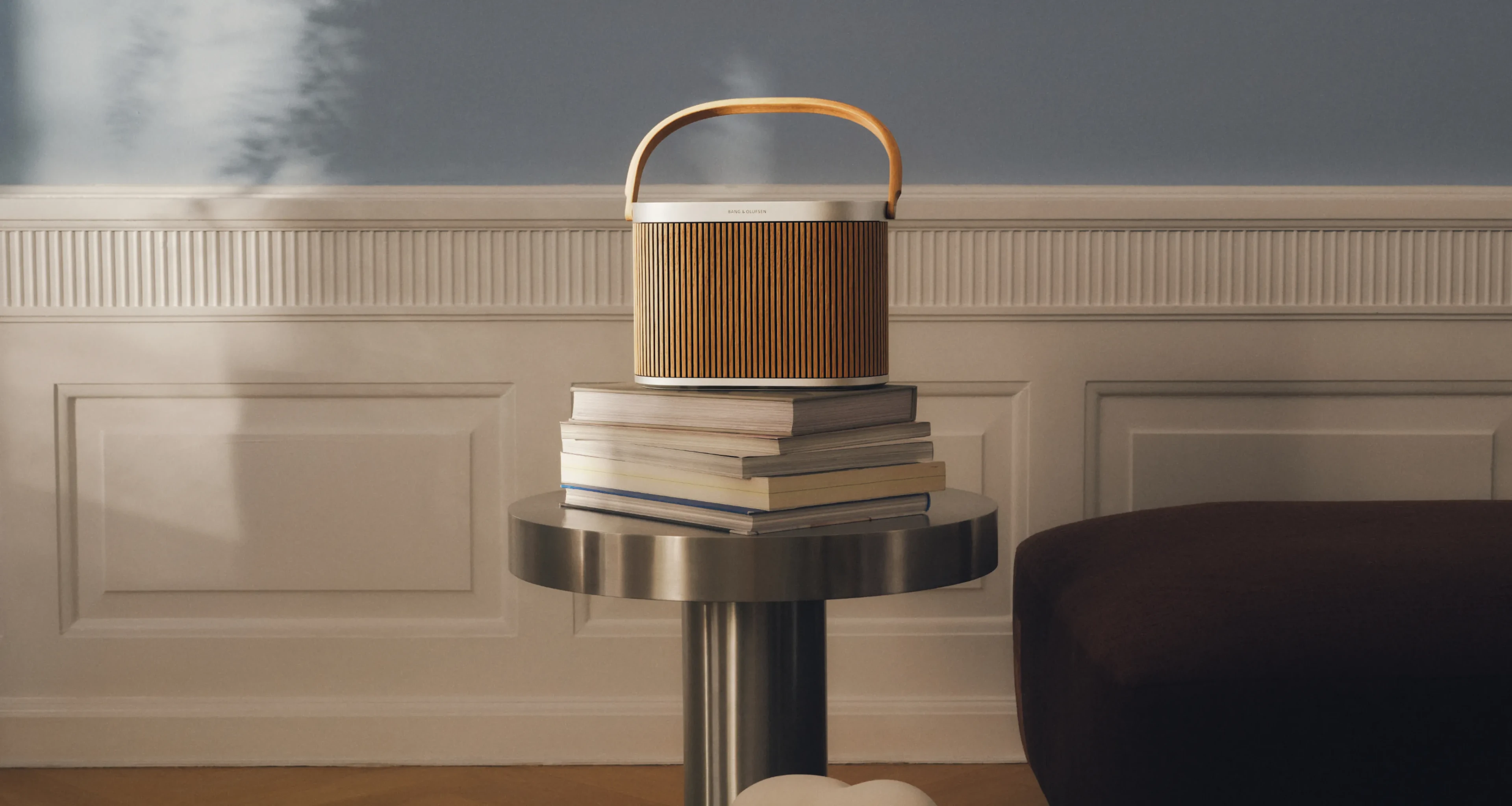 Beosound A5 Oak 擺放於書堆之上，而該書堆則置於看起來像底座的鋁製桌面上