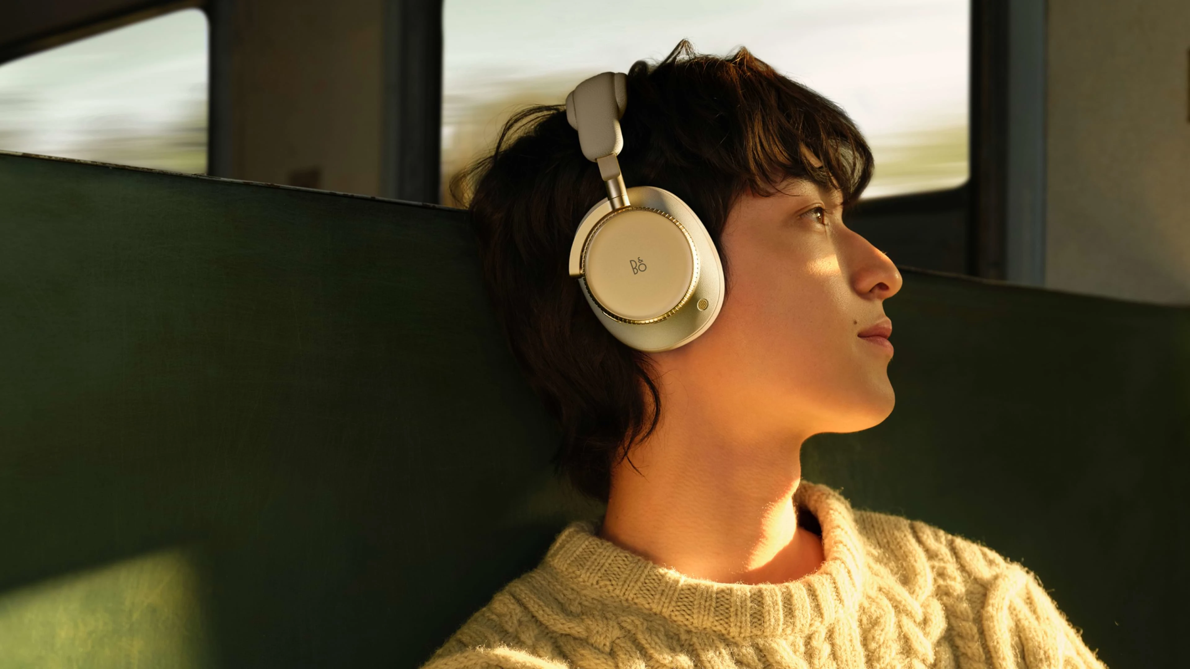 Person sitting in train with the Beoplay H100