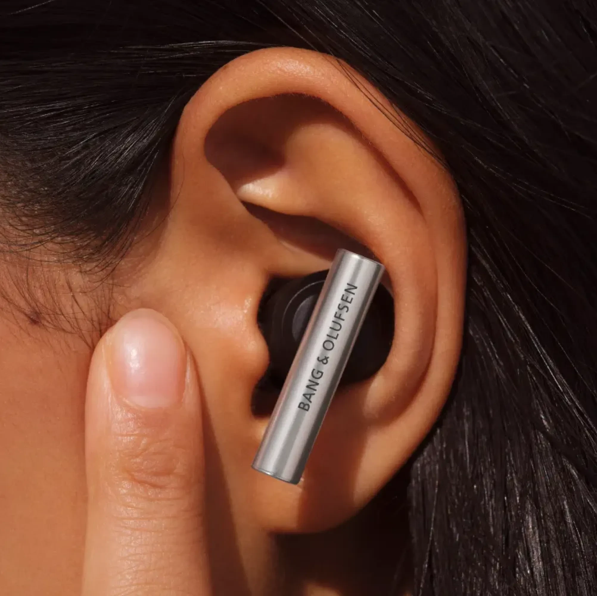 Beo Grace plugged in an ear and a woman touching the skin in front of her ear