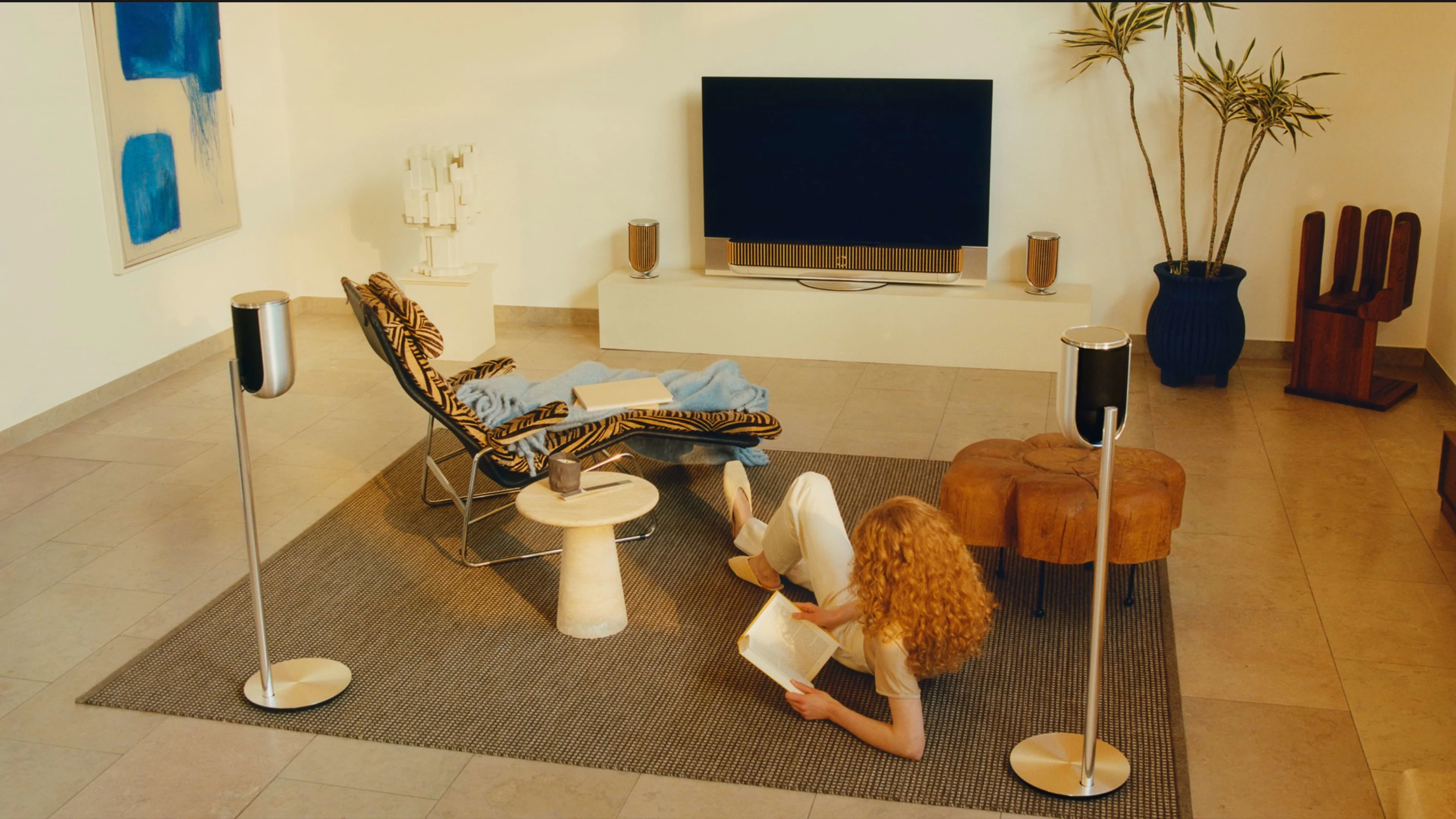 Person sits on floor surrounded by B&O speakers