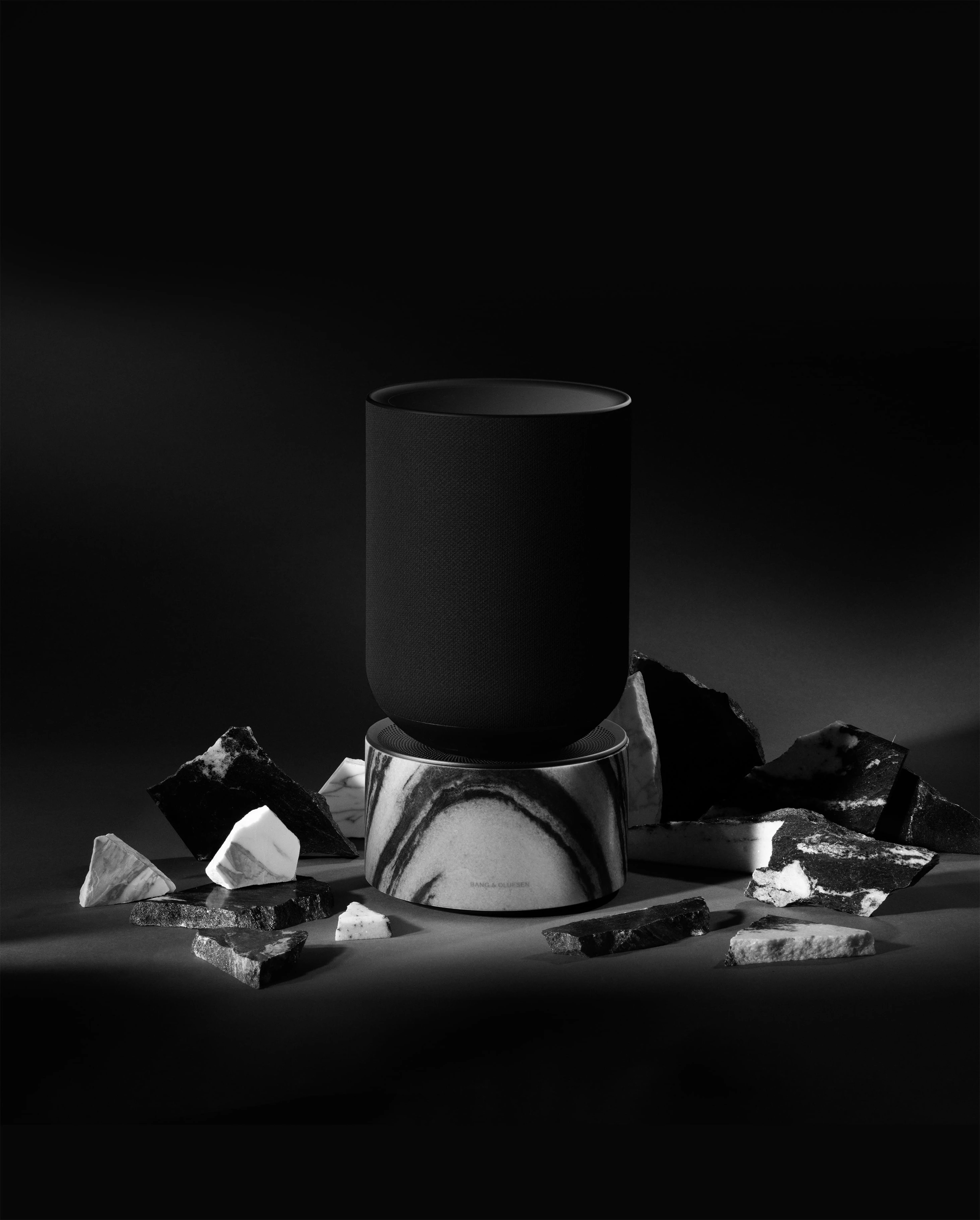 Beosound Balance Marbled Black on a black background with crushed marble