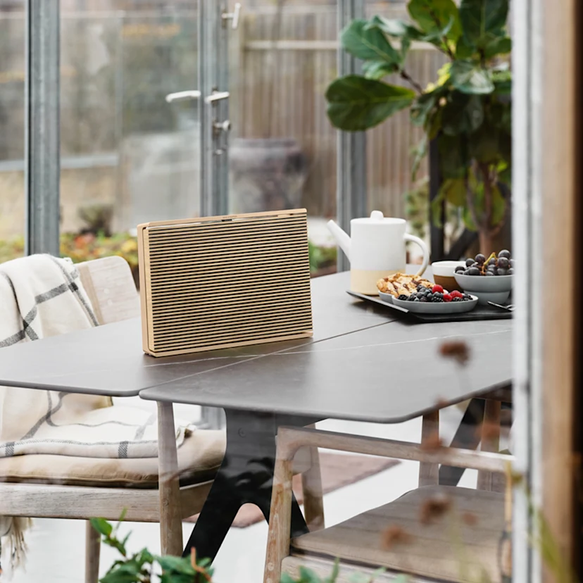 Beosound Level Gold Tone - Light Oak placed upright on a table during breakfast