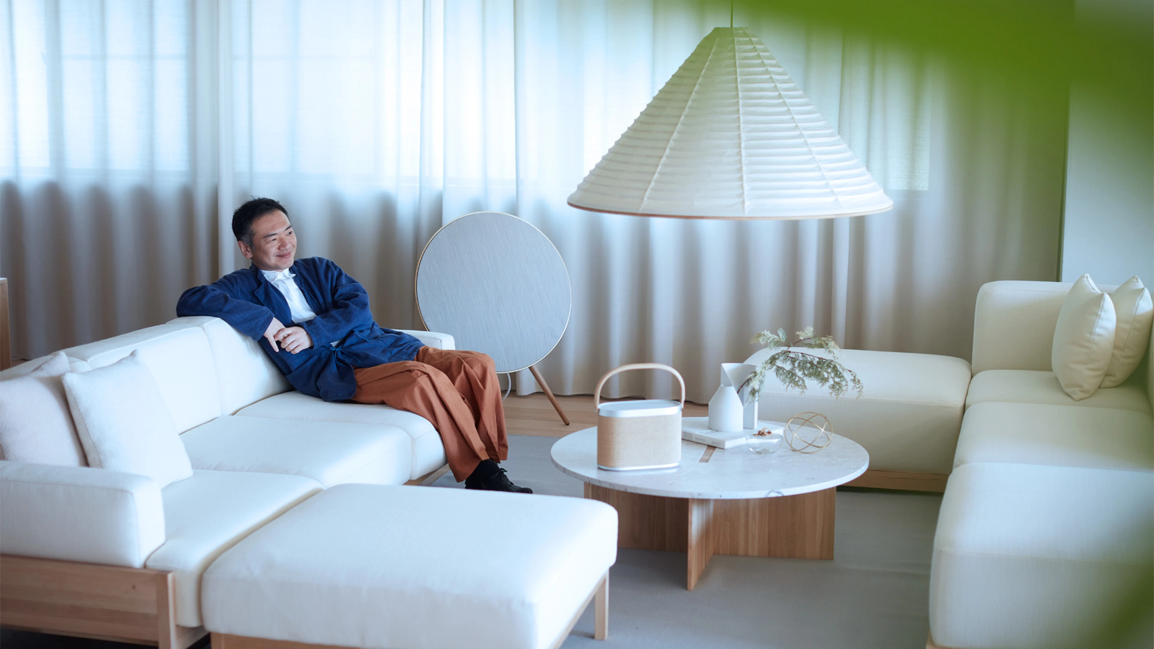 Image of man sitting in a sofa with Beosound A5 on the table