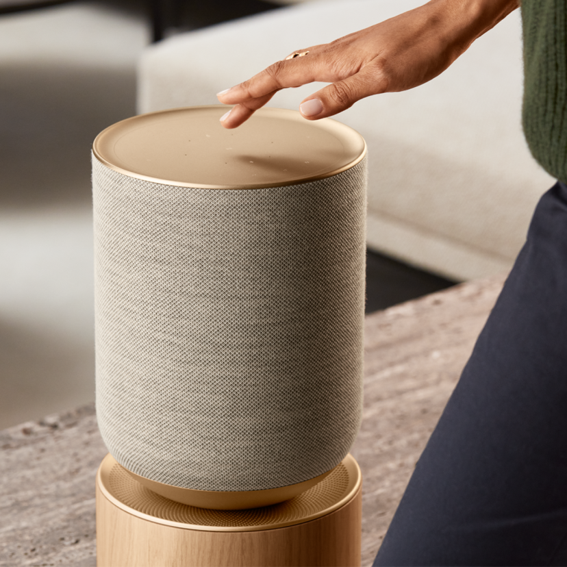 A person using the touch interface on the top of the home speaker Beosound Balance