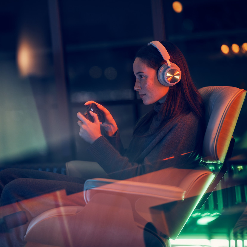 A woman wearing Beoplay Portal headphones for gaming on Xbox