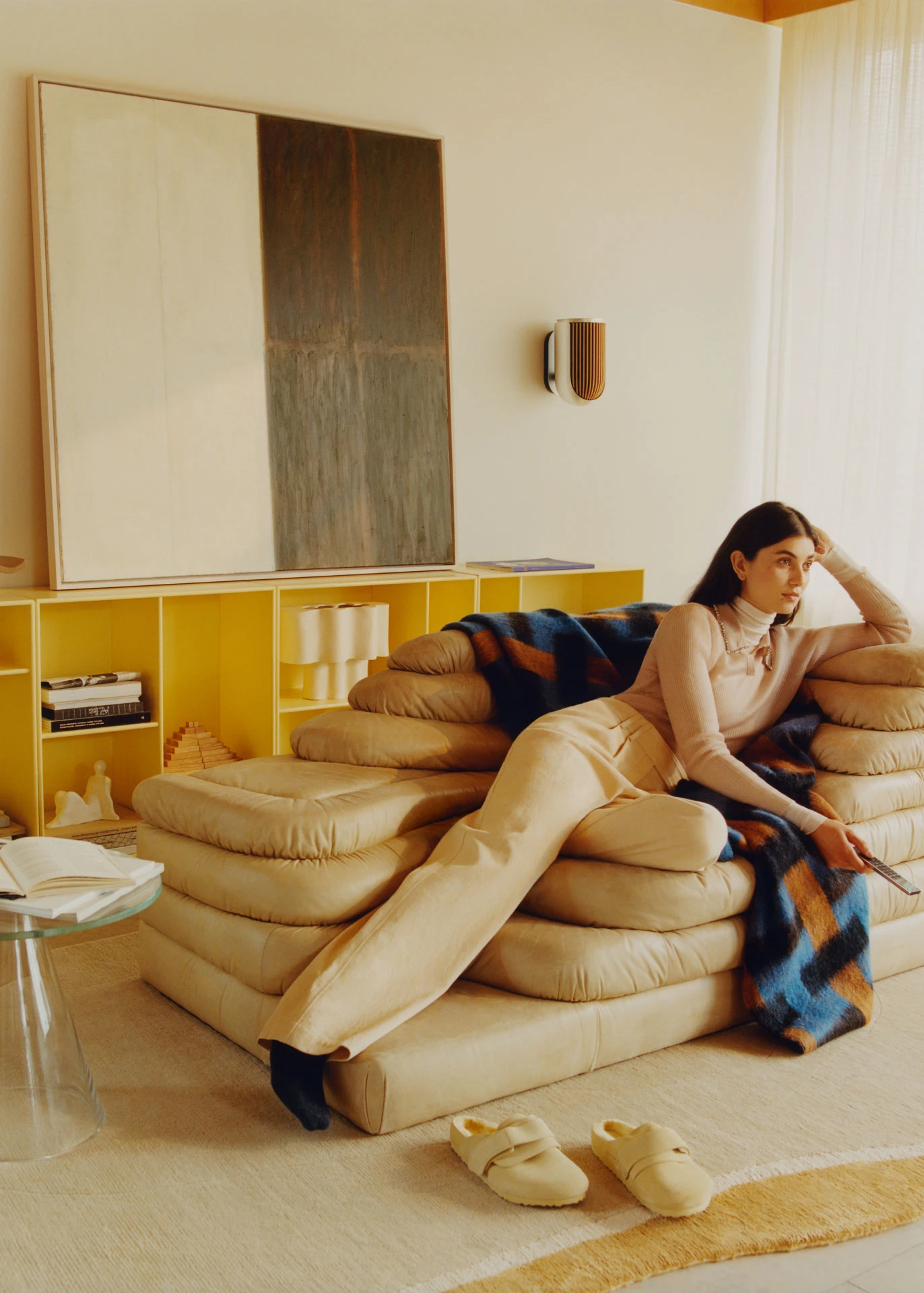 Woman sitting in a lounge chair watching television with Beolab 8 speakers hanging on the wall as rear speakers