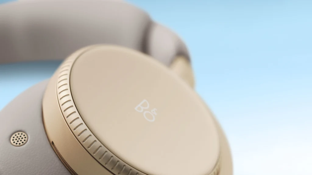 Detail image of the Beoplay H100 headphones in the colour Hourglass Sand with blue background