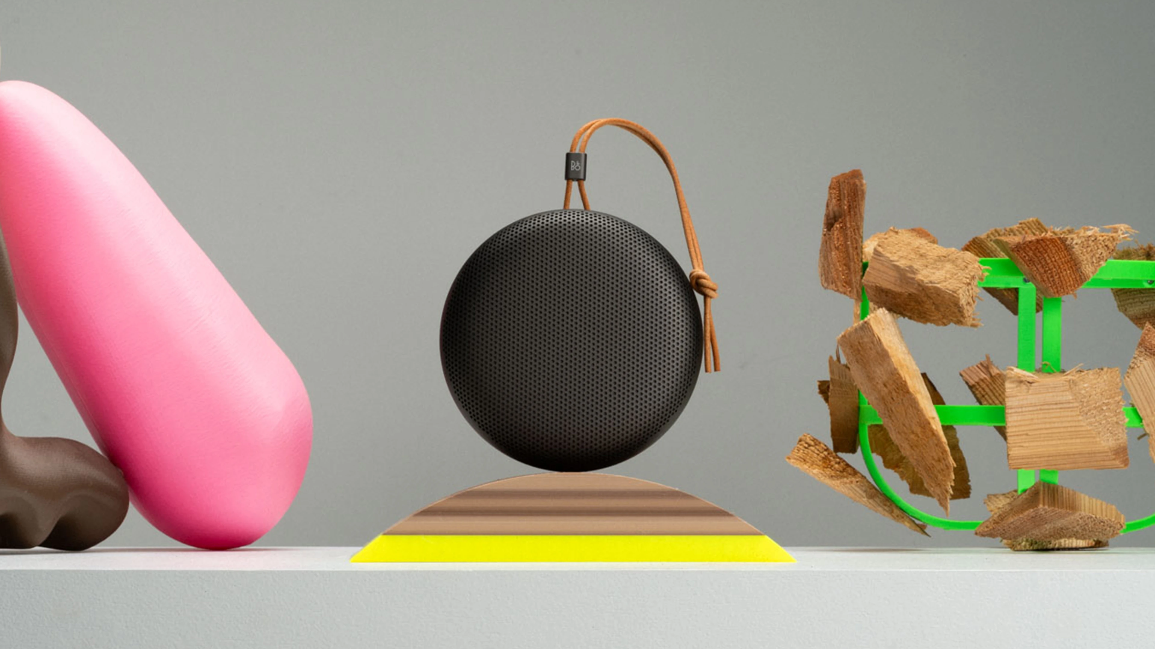 Beosound A1 Warm Granite in between different objects