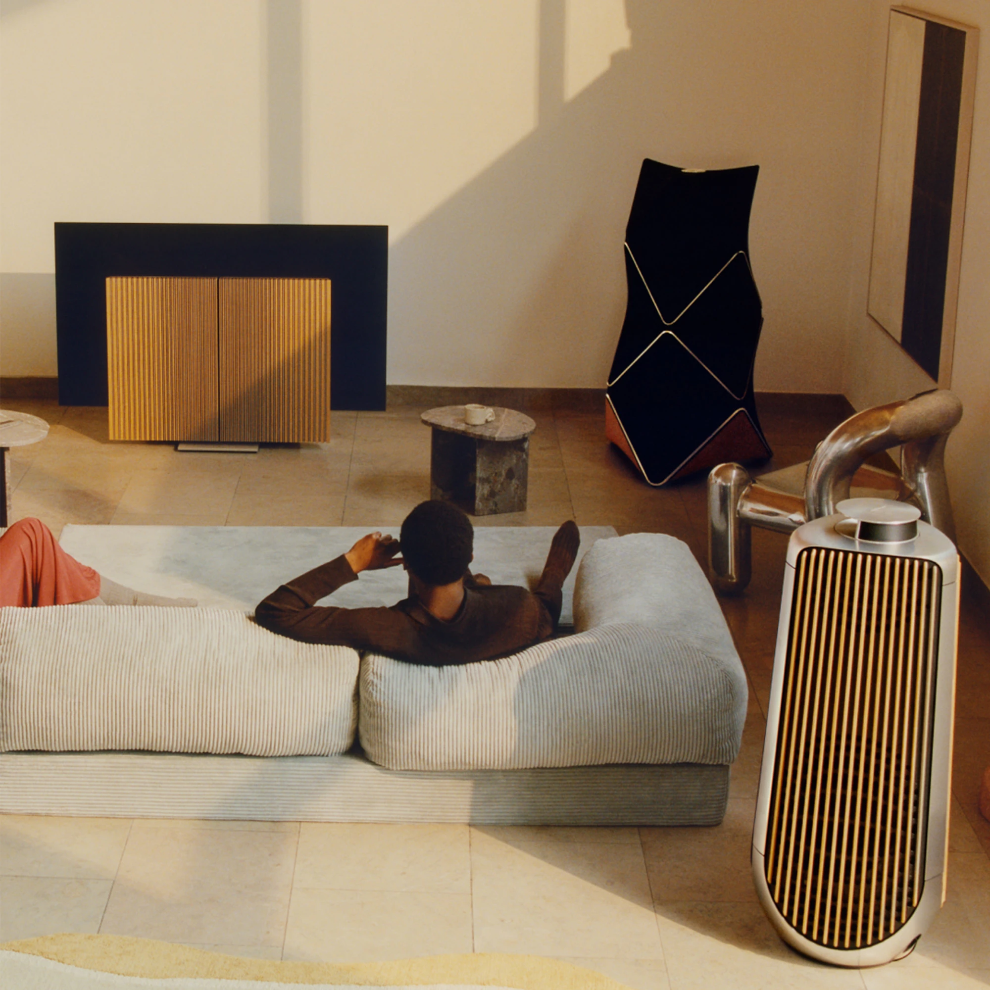 man sitting in room listening to beolab 90 speaker
