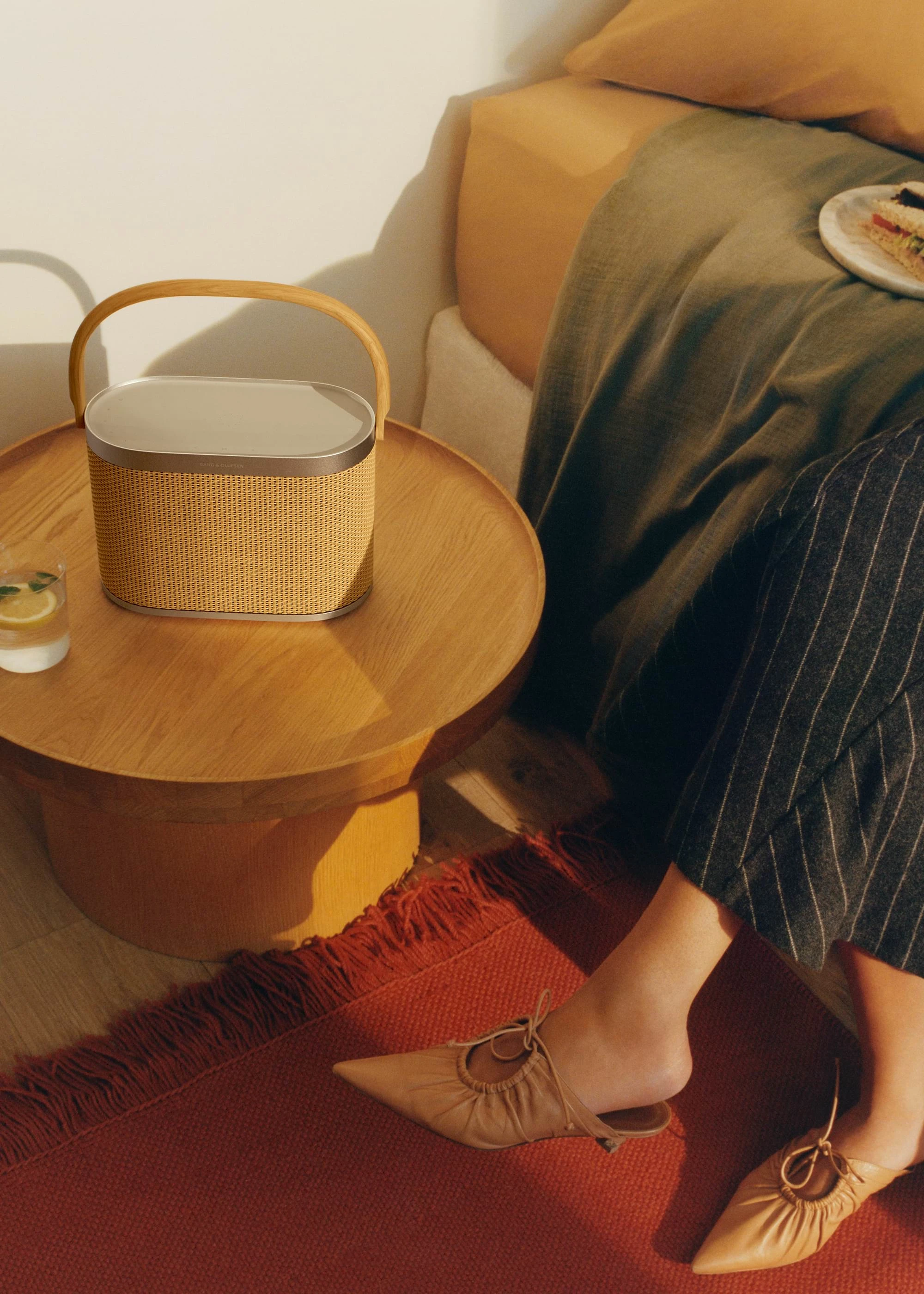 Beosound A5 standing on a table next to a bed