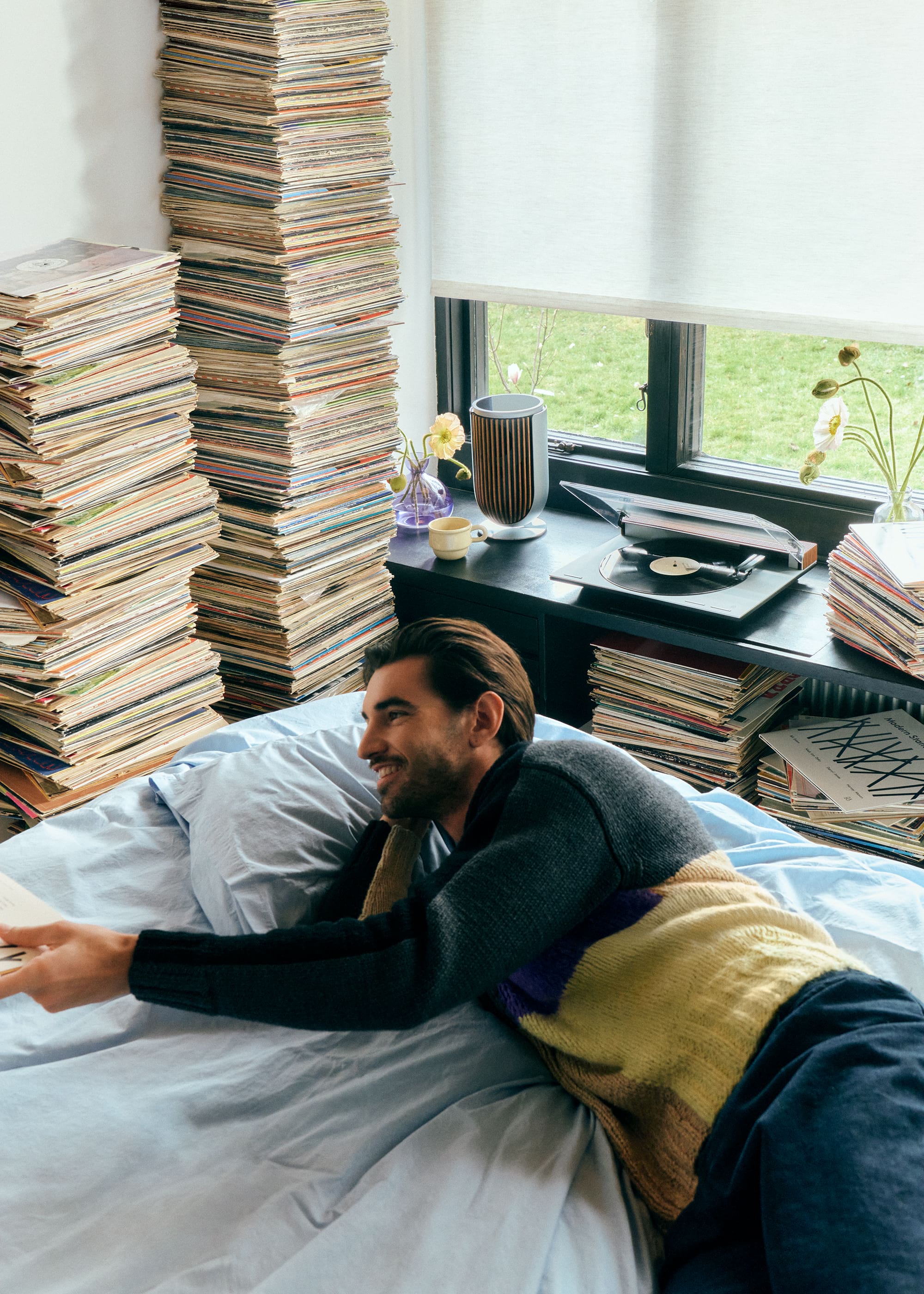 Person laying on bed with vinyls in the background