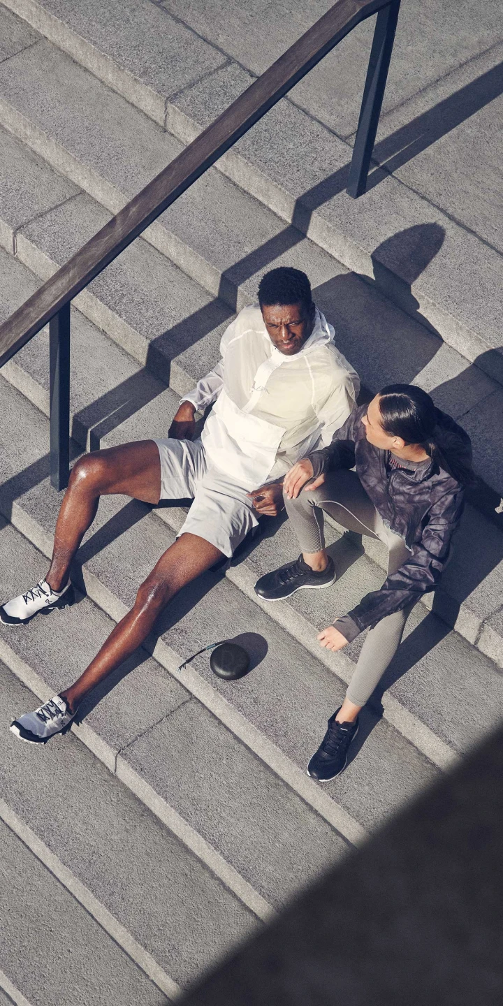 two runners sitting on the stairs listening to music from Beosound A1 2nd gen sport