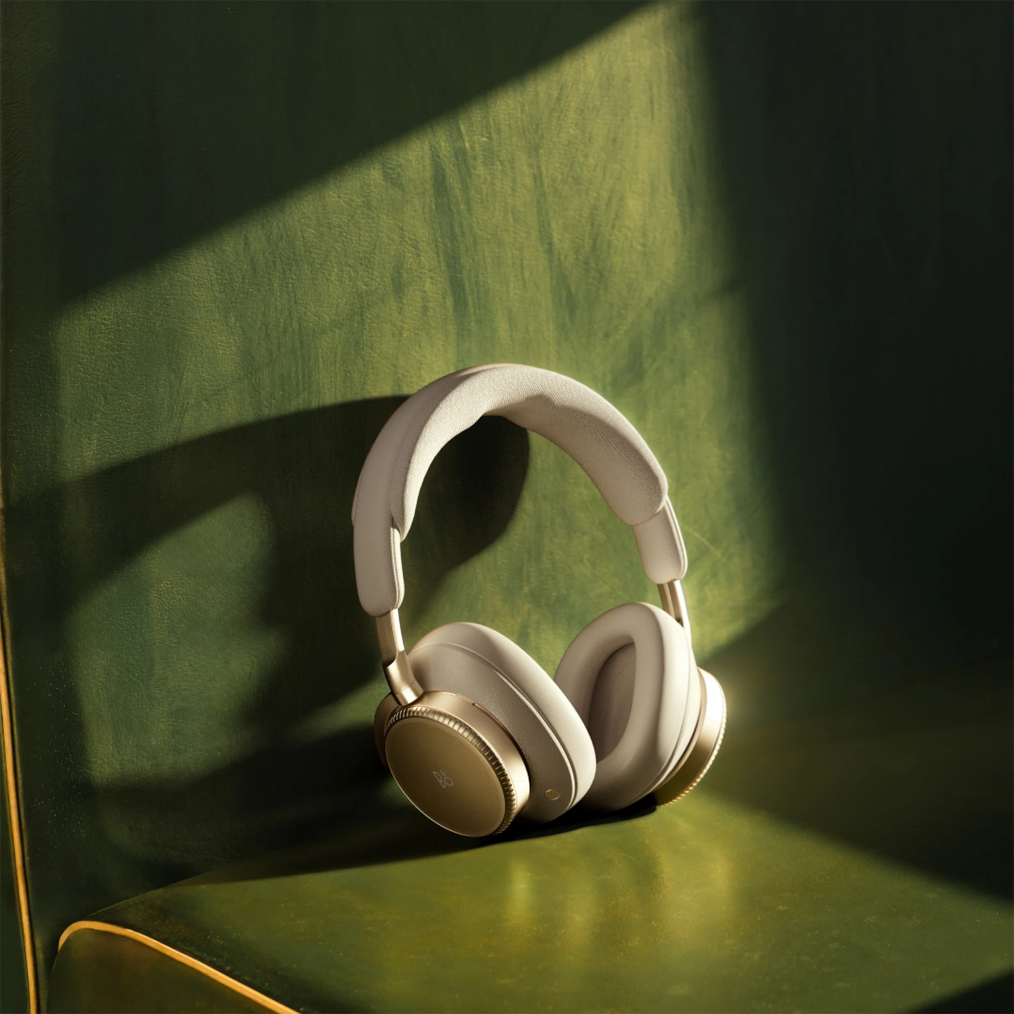 A pair of Beoplay H100 headphones in front of a green background 