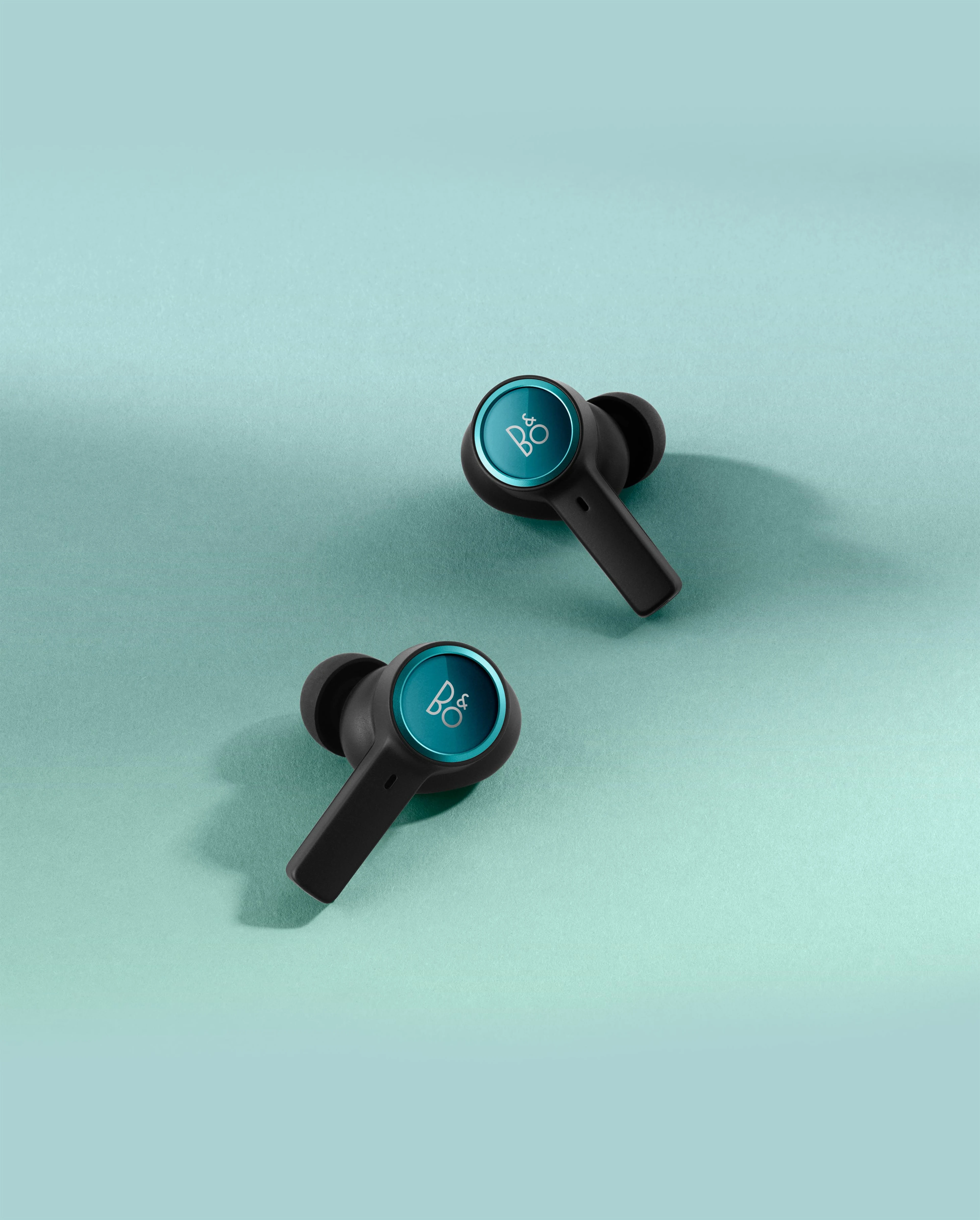 Image of Beoplay EX Northern Sky Turquoise earphones with plain turquoise background