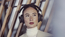 Woman wearing overhear black Beoplay portal headphones 