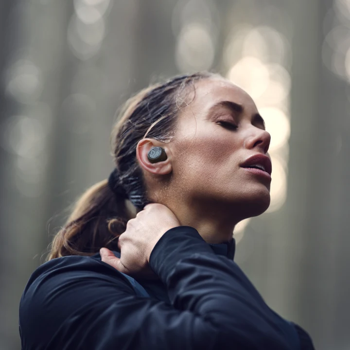 A woman wearing Beoplay E8 sport black earphones while doing exercise