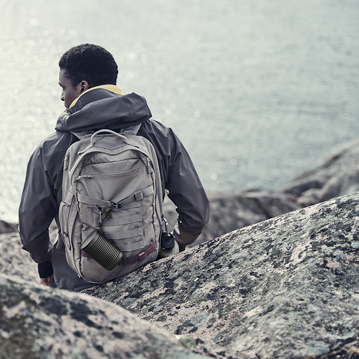 A person carrying Beosound Explore outdoor speaker while hiking