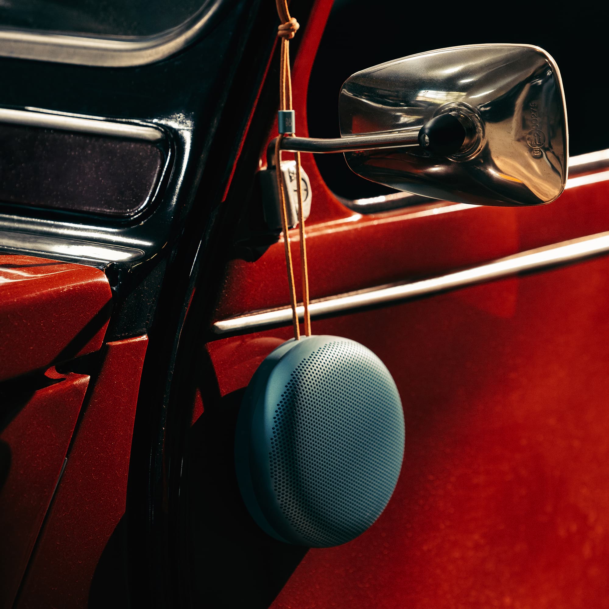 Beosound A1 3rd Gen hanging from a red car