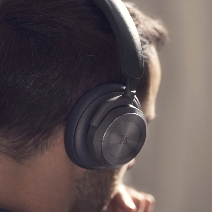 A man wearing the headphones Beoplay HX, with a close view of the right earcup and its touch interface