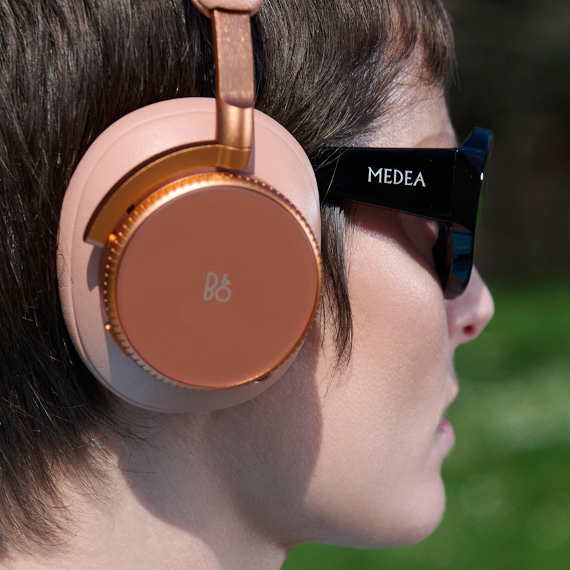 Camilla wearing the Beoplay H100 in sunset apricot