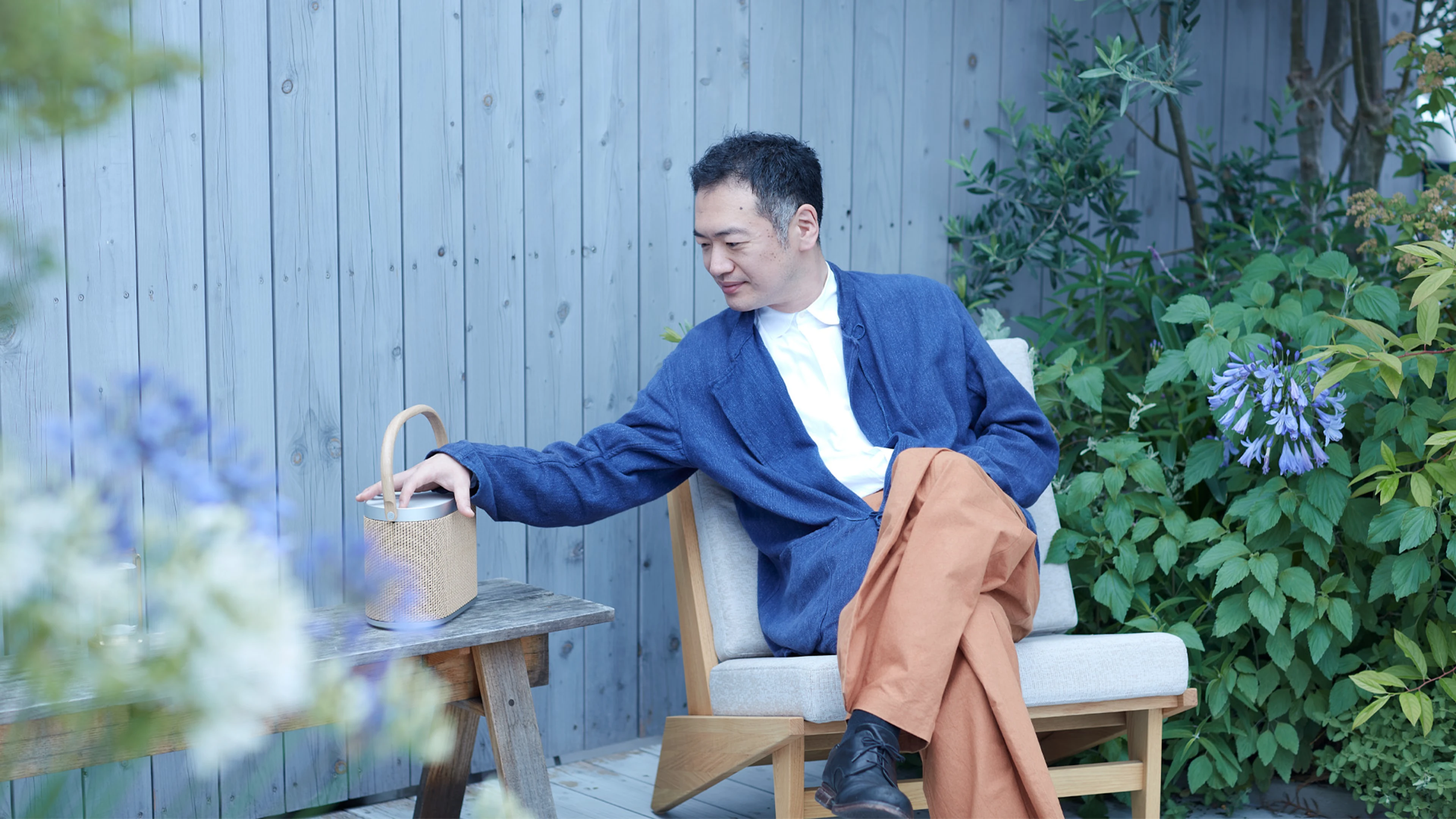 Image of Japanese man sitting in a chair with Beosound A5 on side table