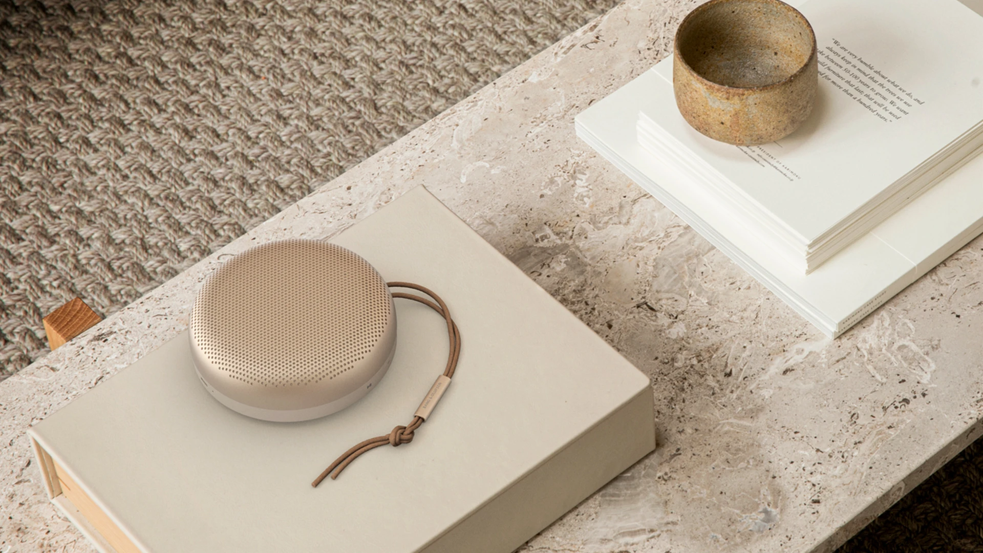 Beoosound A1 bluetooth speaker gold on book on marble desk