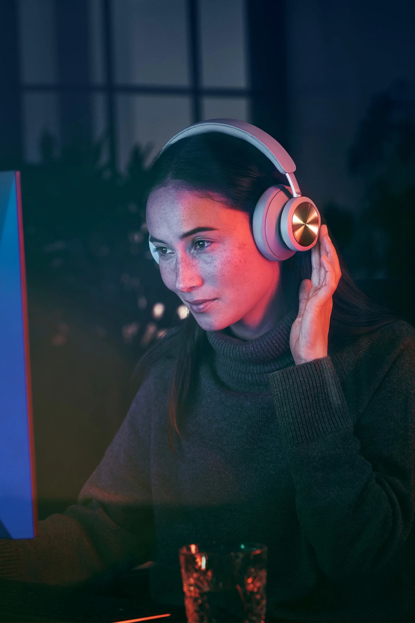 Kulaklıktaki dokunmatik kontrolleri kullanırken Beoplay Portal açıkken bilgisayarında oyun oynayan kadın