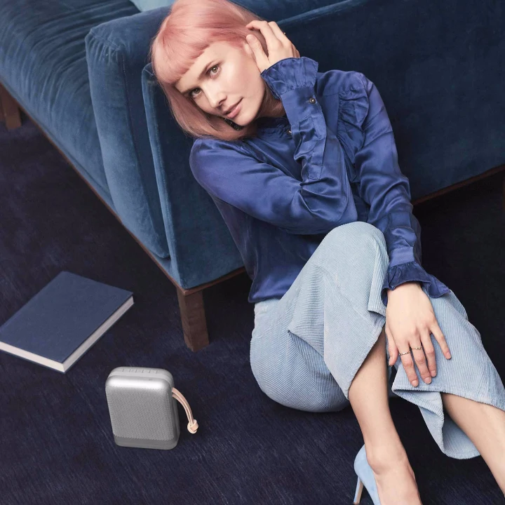 Girl in blue sitting next to couch and beoplay P6
