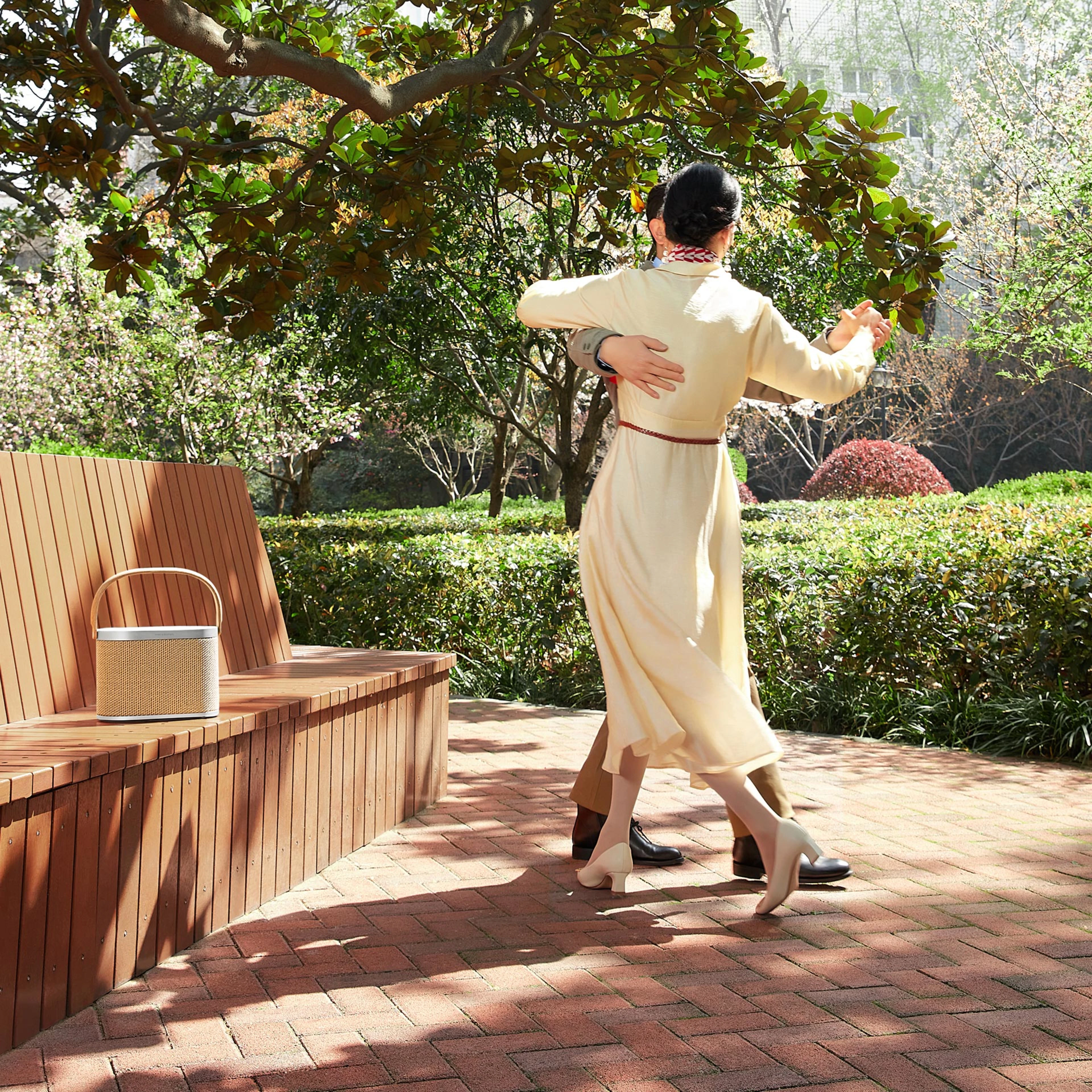 Image of a couple dancing in the park next to the Beosound A5 speaker