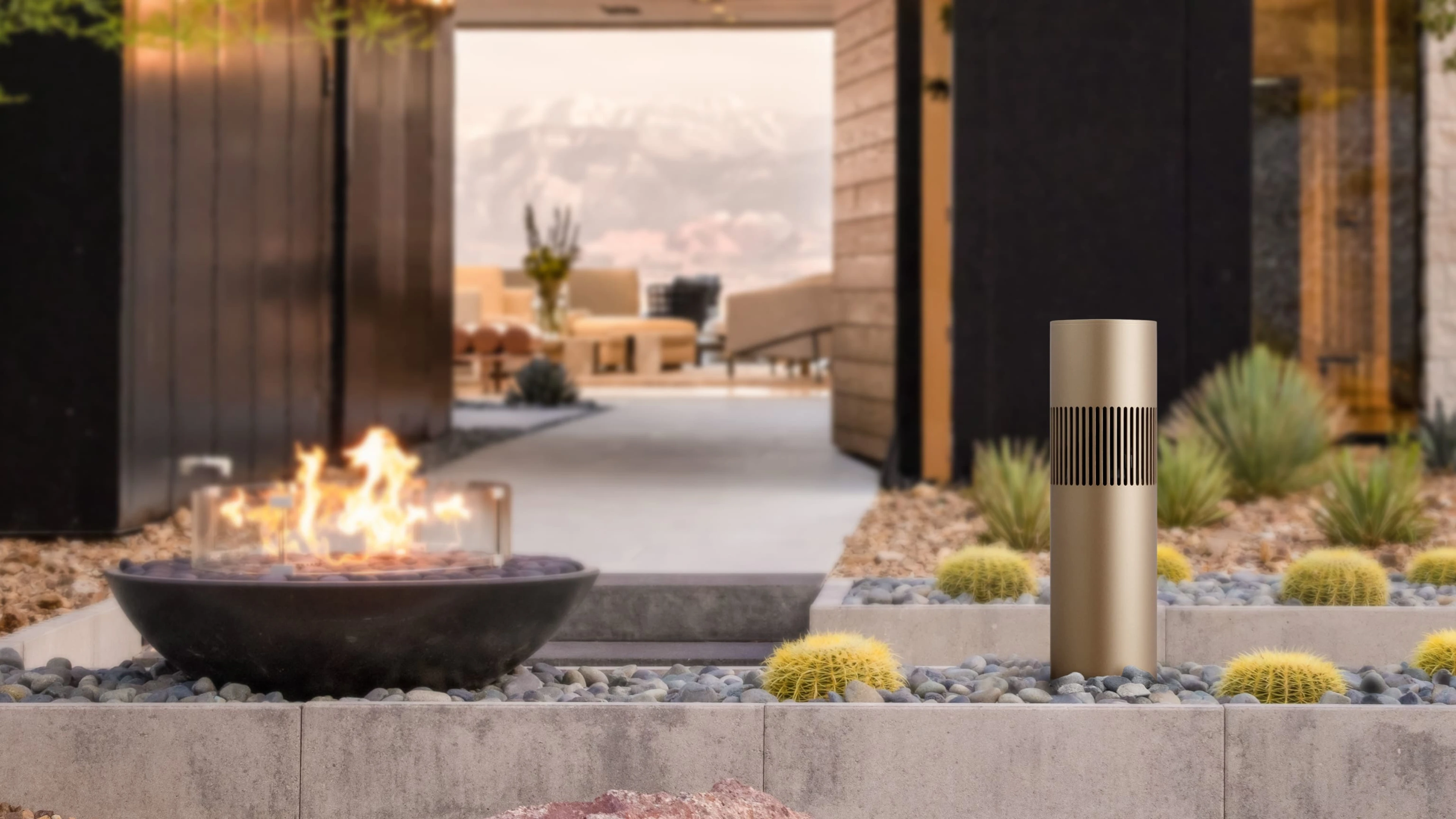 Beosound Bollard in a garden next to an outdoor fireplace