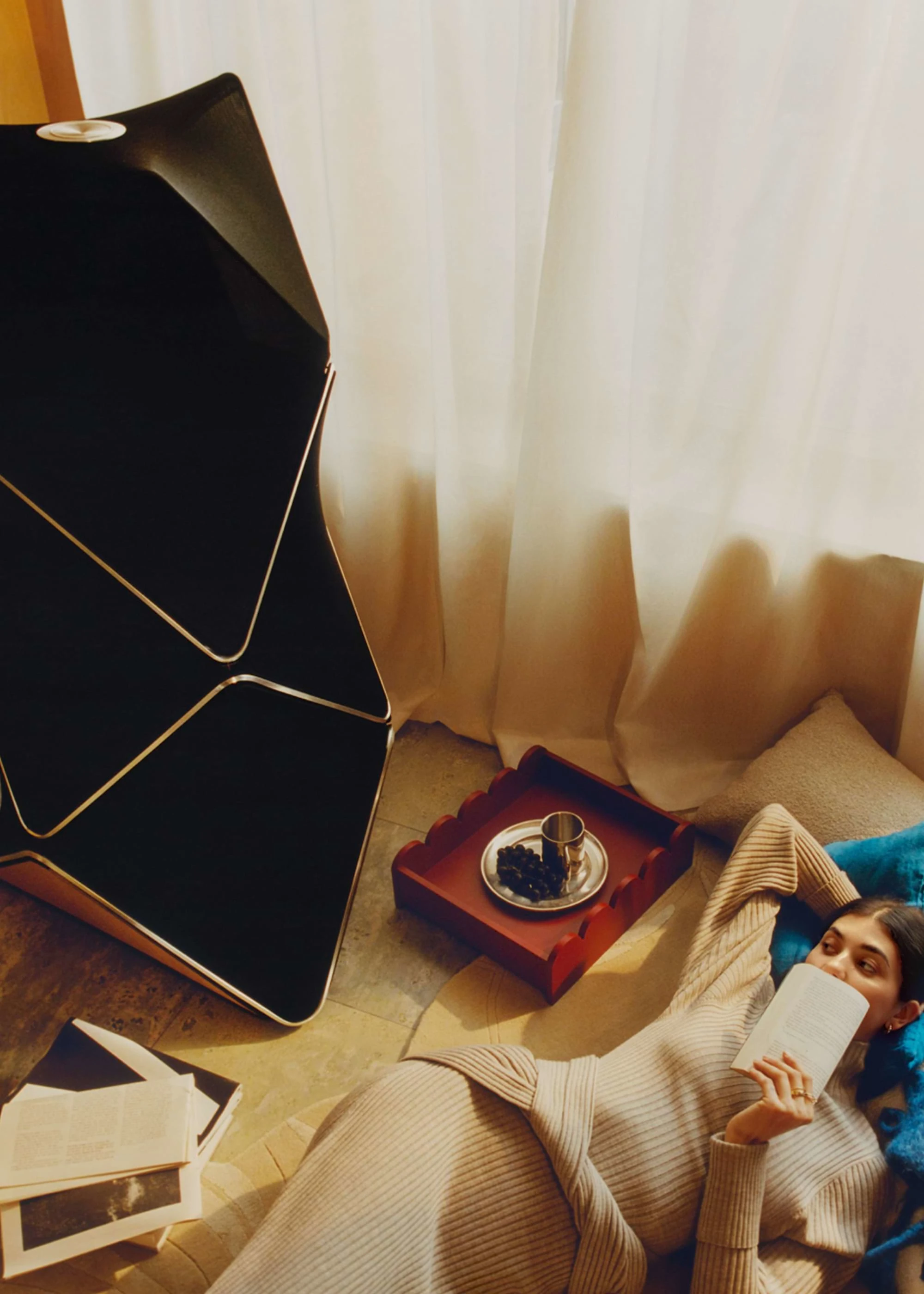 Person laying nex to a Beolab 90 with a book