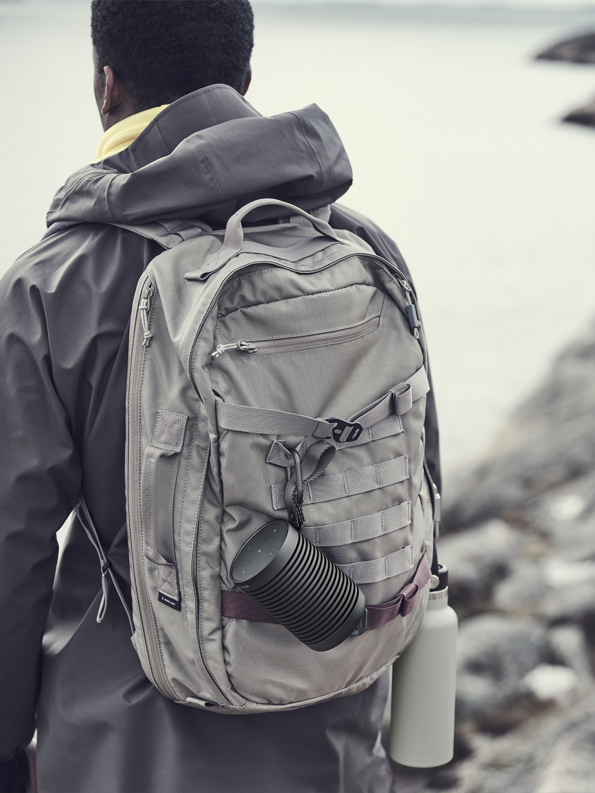 Beosound Explore attached to a backpack with a carabiner during a hike