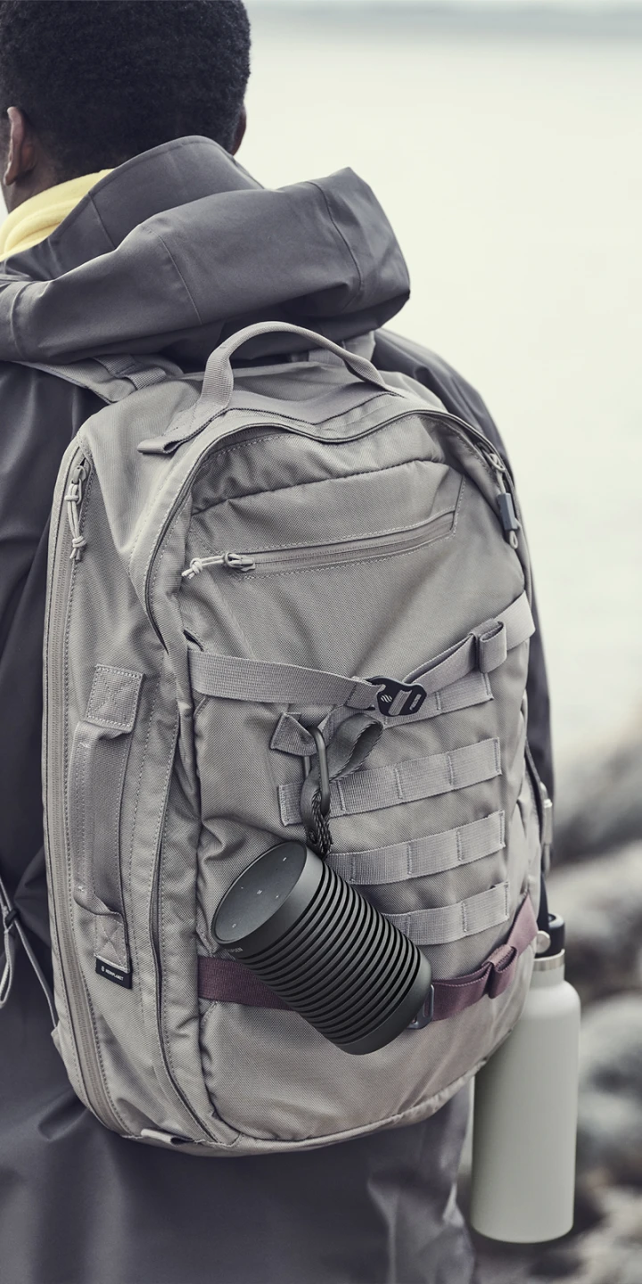 Beosound Explore attached to a backpack with a carabiner during a hike