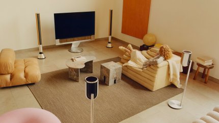 Person sits in living room with a Beovision Theatre, Beolab 28 and Beolab 8