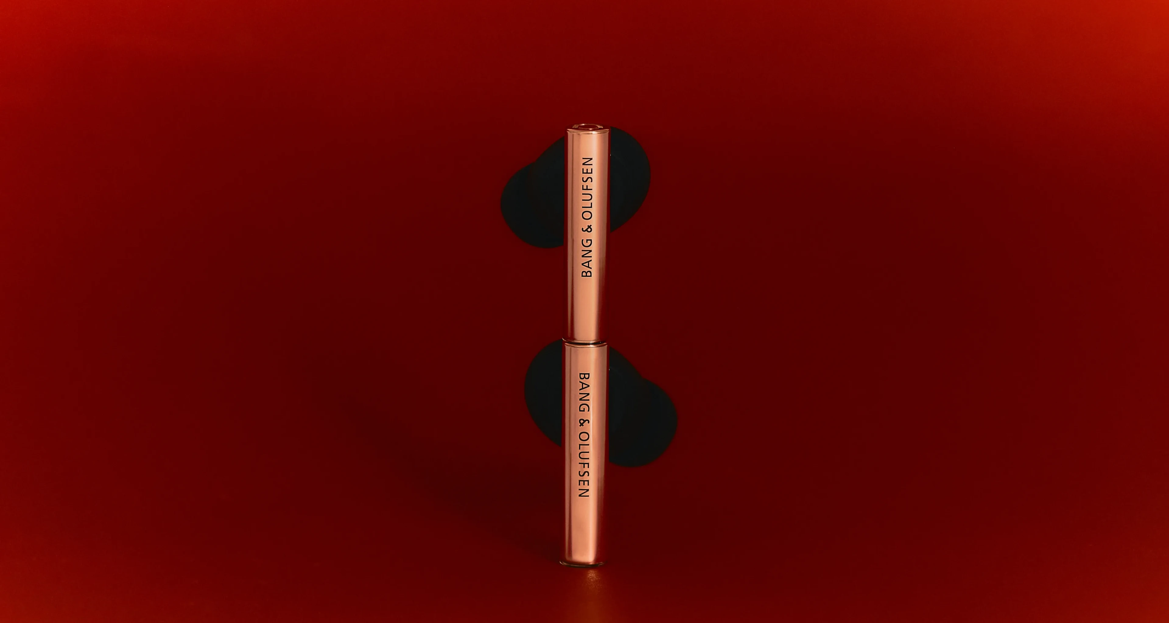 Beo Grace Honey Tone ear phones stack on top of each other on a dark red background.
