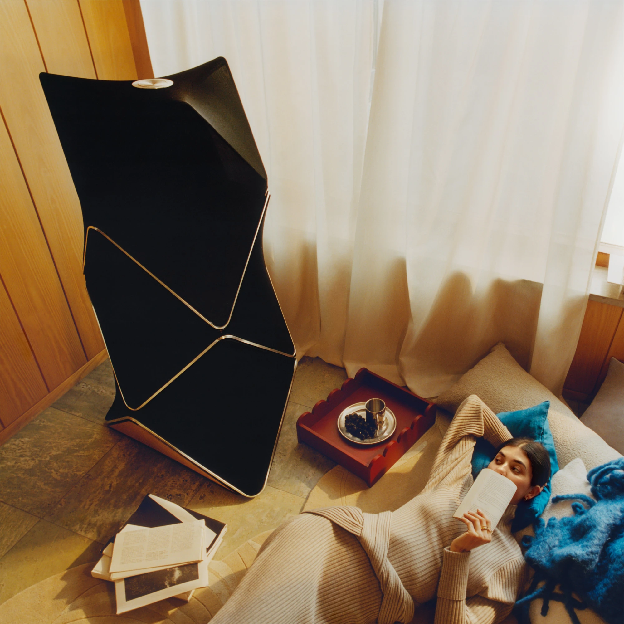 Woman on couch listening to the Beolab 90 speaker